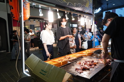 出店でいか焼きを購入する男女