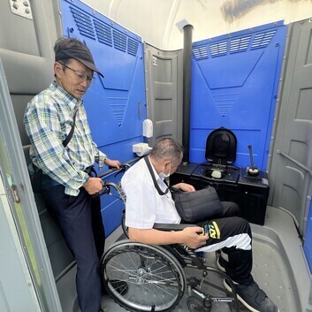 仮設トイレに車いすで入っている写真